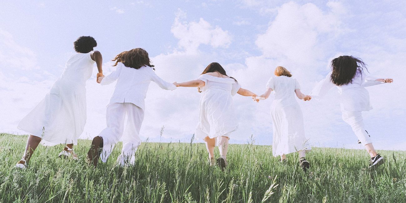 cinque donne vestite di bianco corrono su un prato