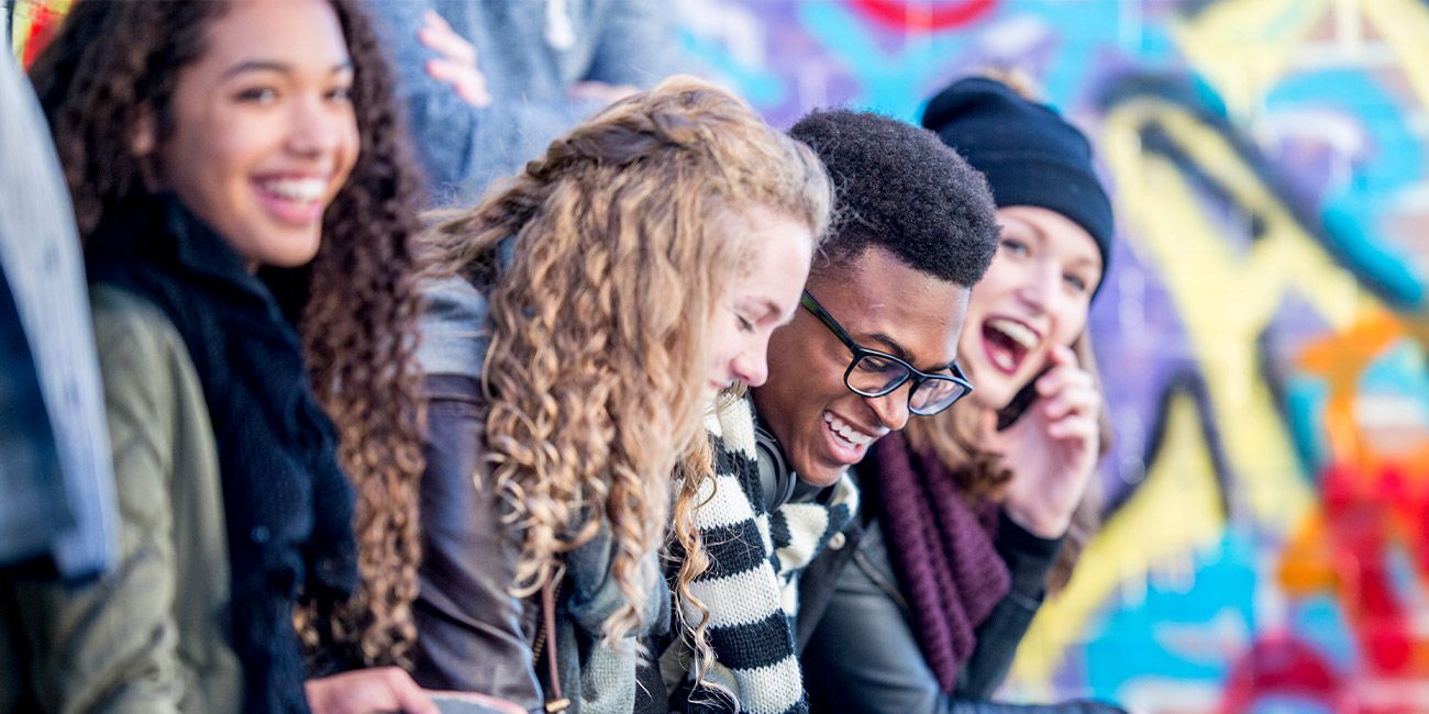 gruppo di ragazzi sorridenti con murales sullo sfondo